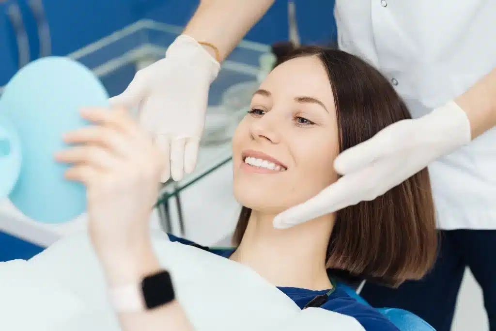 woman looking in the mirror after receiving dental treatment